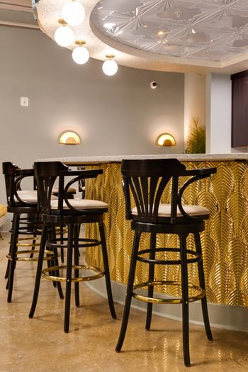 Bar seating with gold palm panel and pendant lights